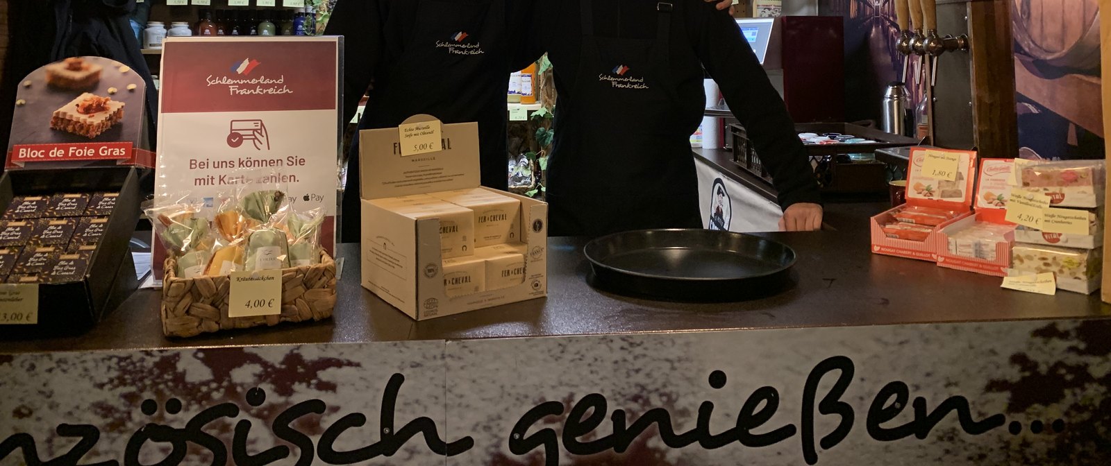 Blick von vorn auf unsere Theke mit Auslage, Schürzen und dem Schriftzug französisch genießen