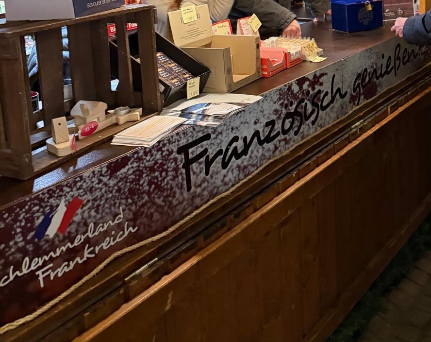 Blick längs über unsere Theke: Holzkiste mit Ware, angebrochene Kartons und der Schriftzug französisch genießen